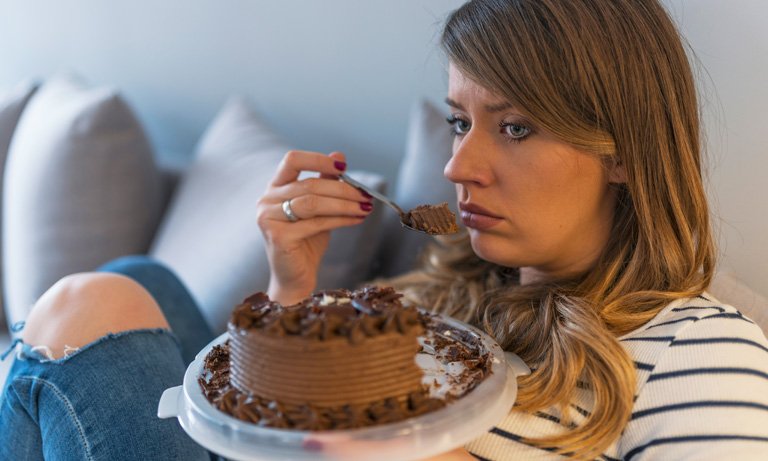 woman eating cake distressed 768 1 - پرخوری عصبی | درمان پرخوری عصبی | روانشناسی پرخوری عصبی