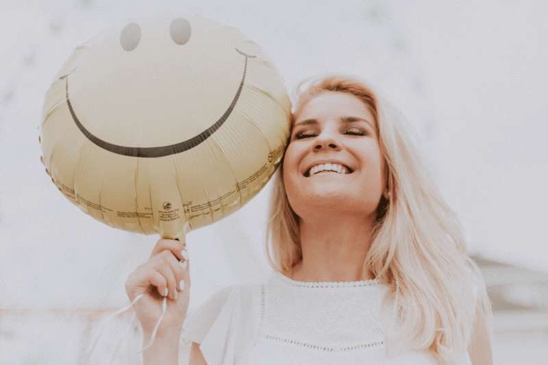 lady with happy face balloon - 8 عادتی که برای رسیدن به خوشبختی نیاز دارید